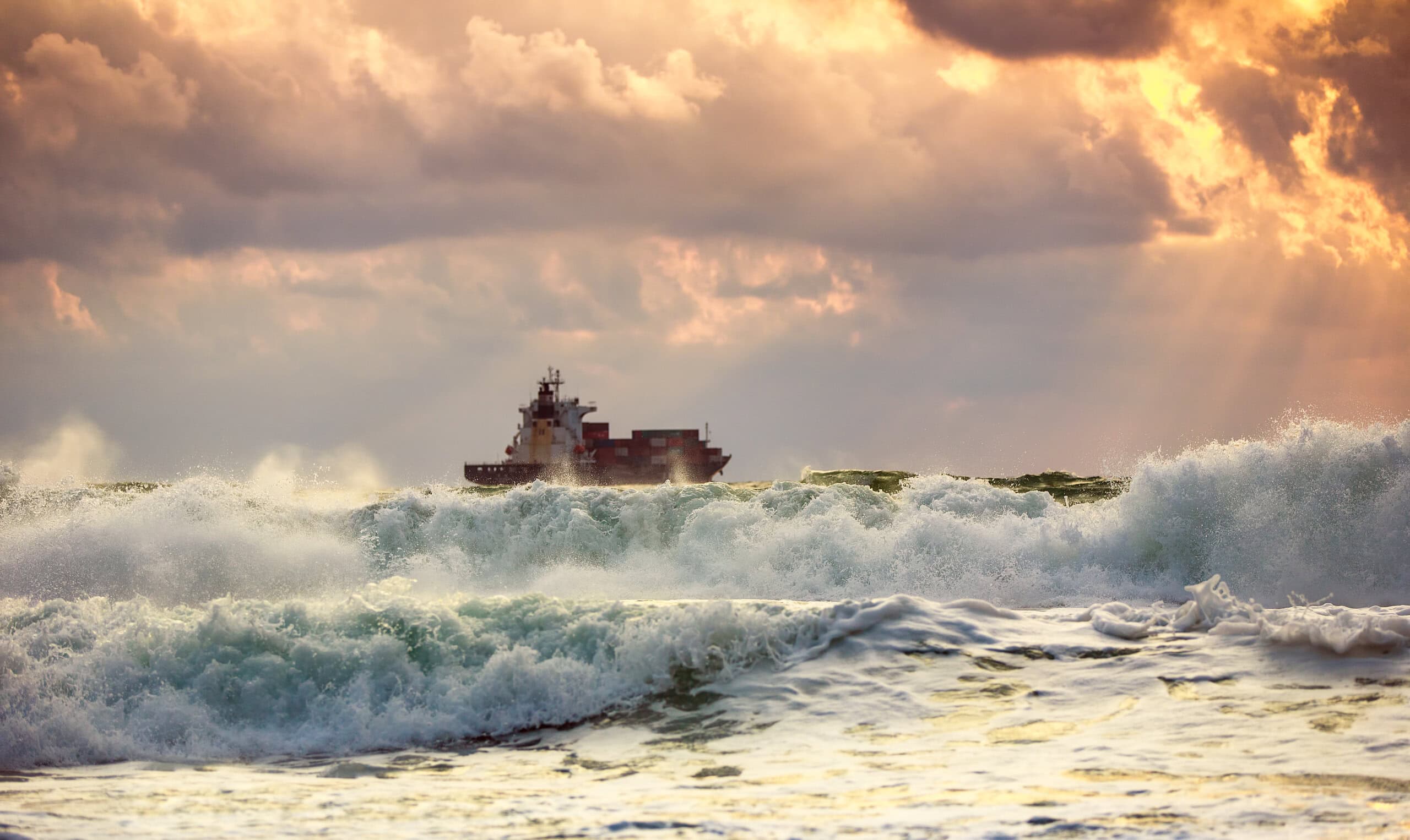 Sun setting at the sea with sailing cargo ship, scenic view