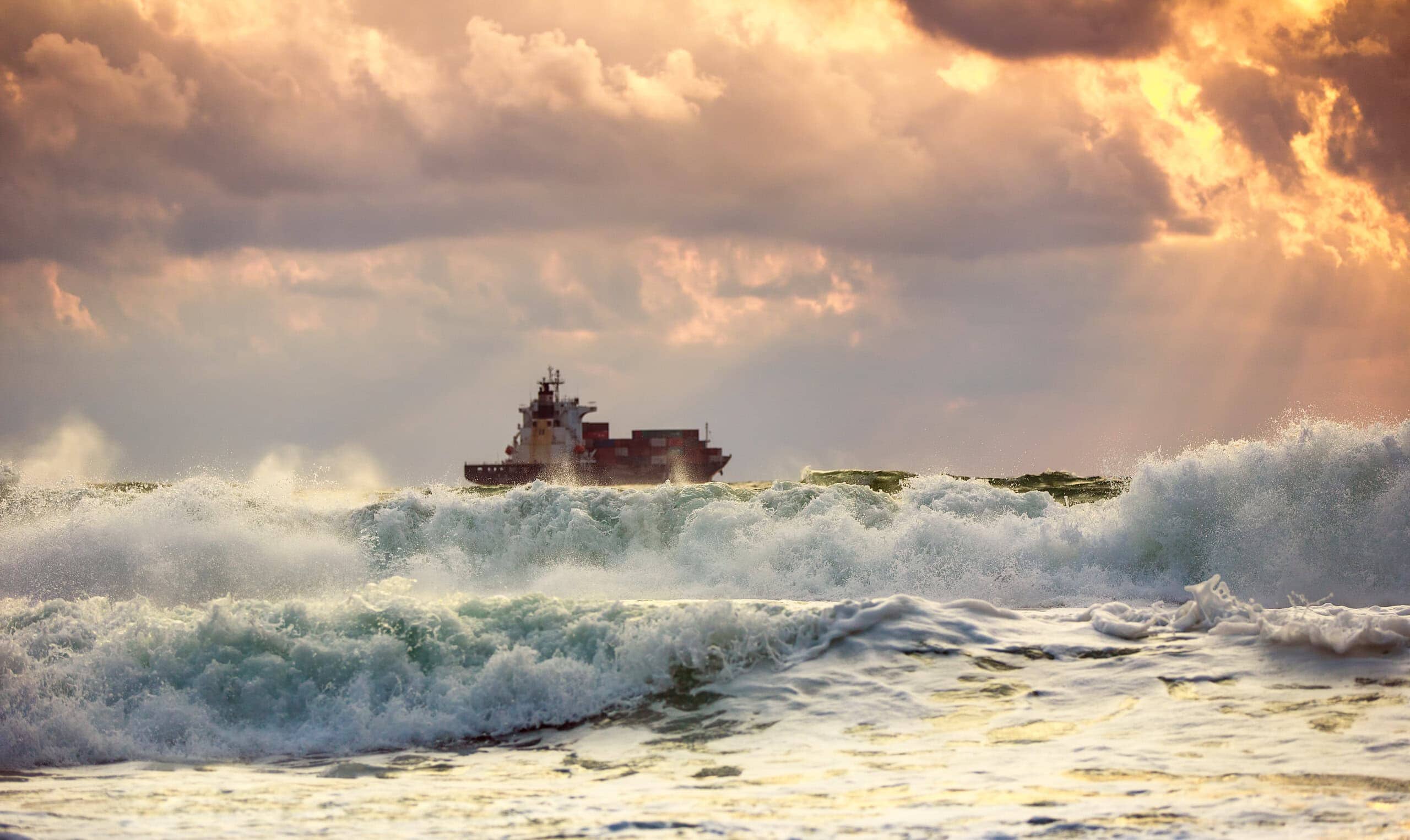 Sun setting at the sea with sailing cargo ship, scenic view